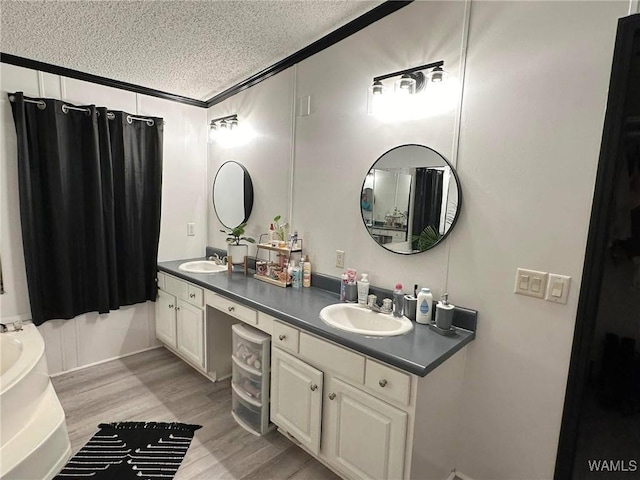 bathroom with wood-type flooring, crown molding, vanity, and a textured ceiling