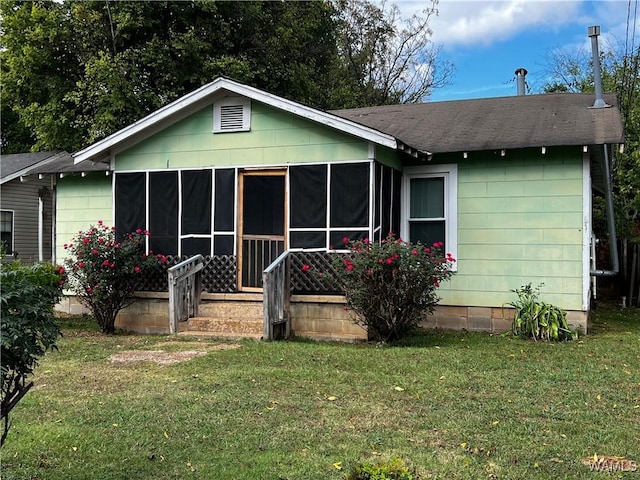 back of house with a yard, roof with shingles, and a sunroom