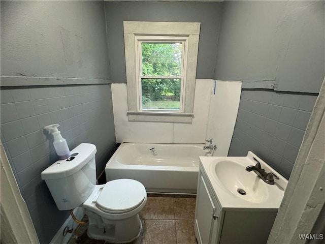 bathroom featuring a washtub, toilet, vanity, wainscoting, and tile walls