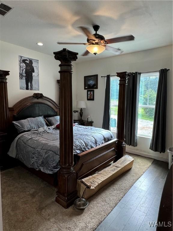 bedroom featuring ceiling fan, wood finished floors, and visible vents