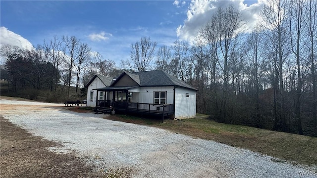 view of front of property with driveway, a shingled roof, and a wooden deck