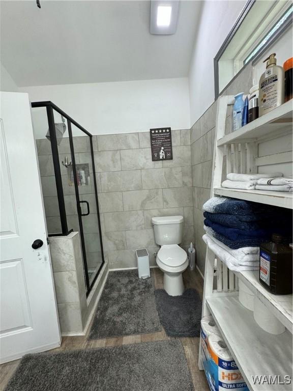 full bath featuring toilet, a stall shower, and tile walls