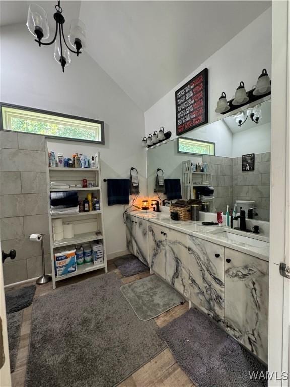 bathroom featuring double vanity, an inviting chandelier, vaulted ceiling, and a sink