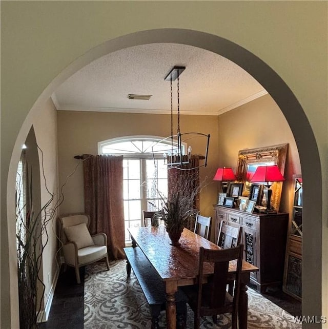 5203 Bristolwood Cir, Northport, AL 35475 - dining area featuring arched walkways, a textured ceiling, a chandelier, and crown molding