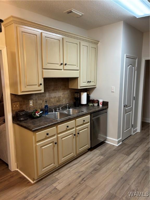 5203 Bristolwood Cir, Northport, AL 35475 - kitchen featuring dishwasher, cream cabinetry, light wood-type flooring, decorative backsplash, and dark countertops