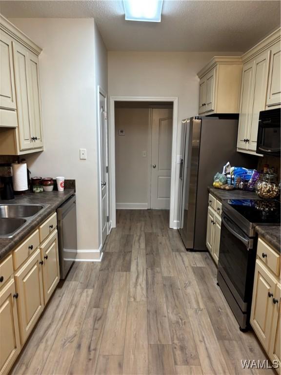 5203 Bristolwood Cir, Northport, AL 35475 - kitchen with cream cabinets, dark countertops, stainless steel appliances, light wood-type flooring, and exhaust hood