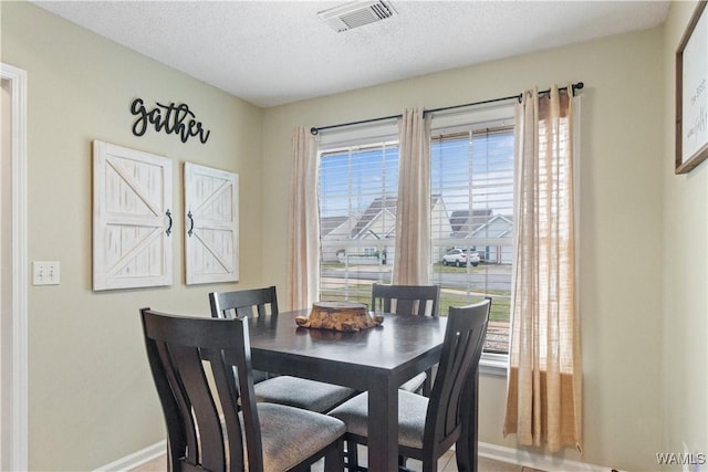 dining room featuring visible vents, baseboards, and a textured ceiling