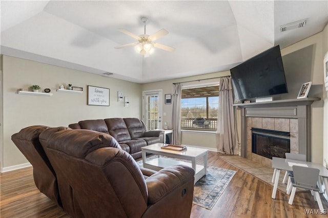 living room with wood finished floors, baseboards, visible vents, a fireplace, and ceiling fan