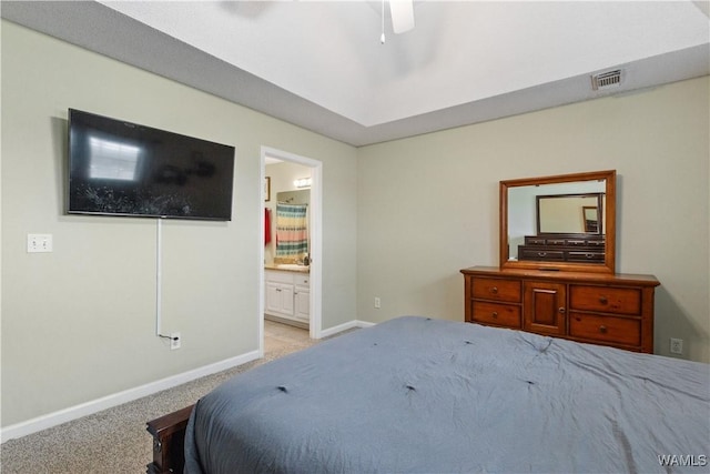 bedroom with ensuite bath, baseboards, visible vents, and light carpet