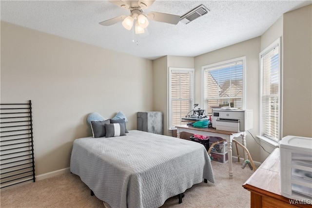 carpeted bedroom featuring a ceiling fan, baseboards, visible vents, and a textured ceiling