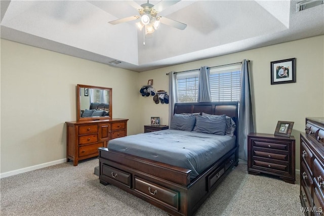 bedroom featuring visible vents, baseboards, light colored carpet, lofted ceiling, and a raised ceiling