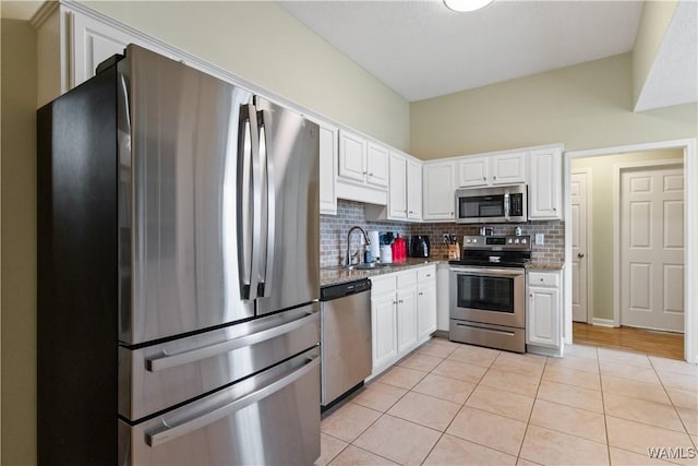 kitchen with backsplash, appliances with stainless steel finishes, white cabinets, and a sink