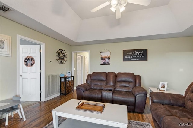 living area featuring dark wood finished floors, visible vents, a tray ceiling, and a ceiling fan