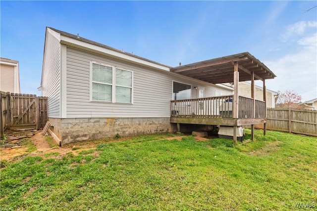 back of house featuring a deck, a fenced backyard, and a lawn