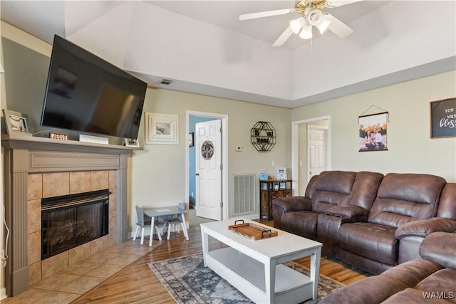 living area with a fireplace, wood finished floors, a ceiling fan, and visible vents