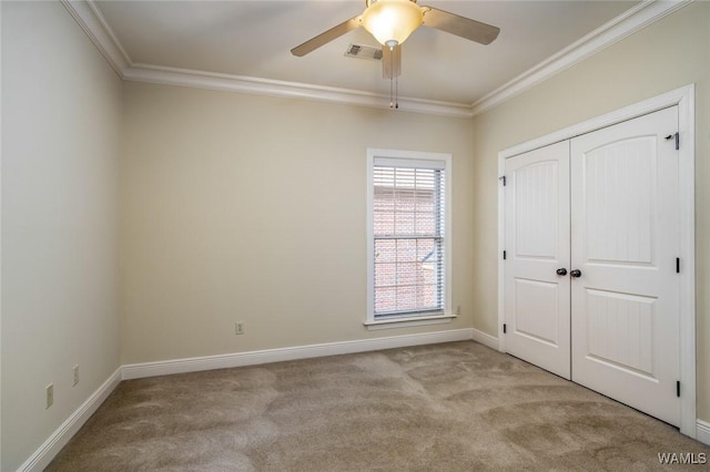 unfurnished bedroom featuring a closet, crown molding, light colored carpet, and ceiling fan