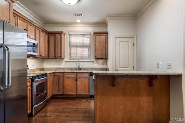 kitchen featuring a breakfast bar area, stainless steel appliances, ornamental molding, sink, and kitchen peninsula