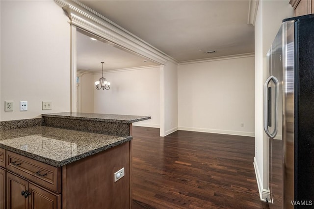 kitchen featuring dark stone counters, stainless steel fridge with ice dispenser, crown molding, kitchen peninsula, and hanging light fixtures