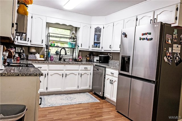 2516 17th Ave, Northport, AL 35476 - kitchen featuring a sink, light wood finished floors, stainless steel appliances, white cabinets, and dark stone counters