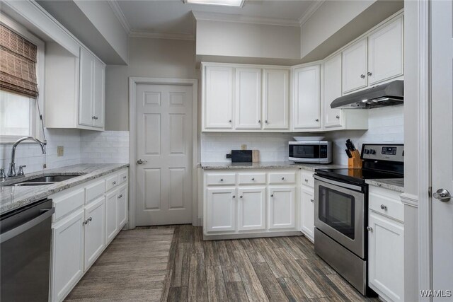 kitchen featuring appliances with stainless steel finishes, crown molding, under cabinet range hood, white cabinetry, and a sink