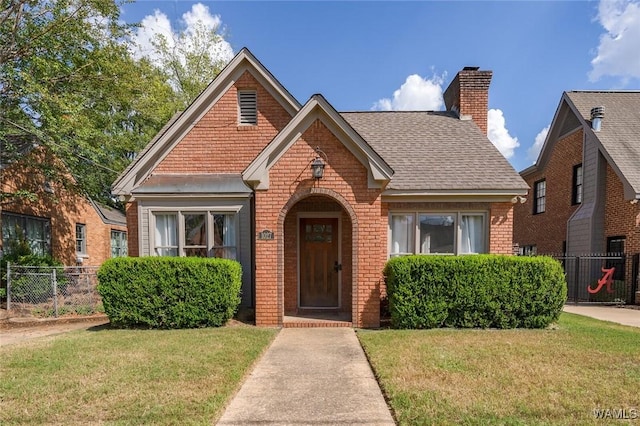 view of front facade with a chimney, fence, a front lawn, and brick siding