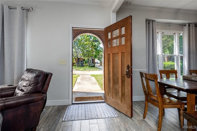 foyer with dark wood-type flooring, crown molding, and baseboards