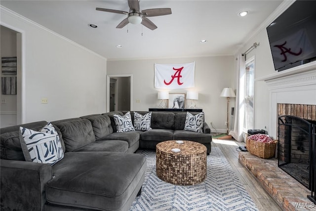 living room featuring ceiling fan, a brick fireplace, wood finished floors, and crown molding