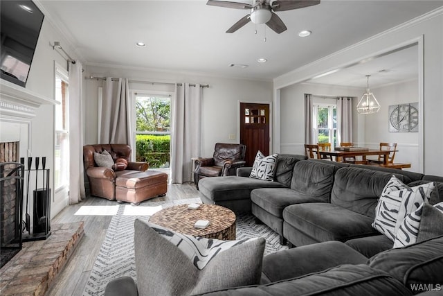 living room featuring a fireplace with raised hearth, crown molding, light wood-style flooring, and a healthy amount of sunlight