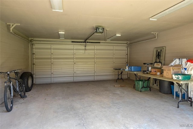 garage featuring concrete block wall and a garage door opener