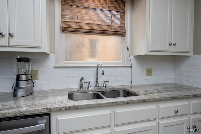 kitchen with dishwasher, light stone counters, a sink, and white cabinets