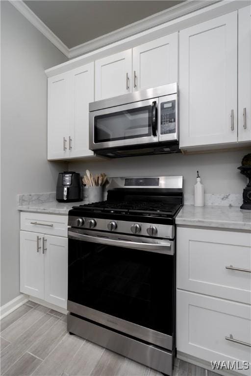 2603 Lauren St, Northport, AL 35475 - kitchen featuring stainless steel appliances, ornamental molding, white cabinetry, light wood-type flooring, and light stone counters