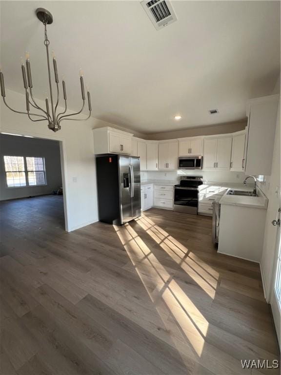 kitchen with dark wood-type flooring, pendant lighting, white cabinetry, appliances with stainless steel finishes, and sink