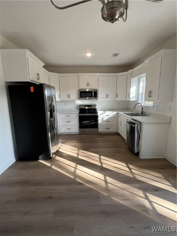 kitchen featuring appliances with stainless steel finishes, dark wood-type flooring, white cabinetry, and sink