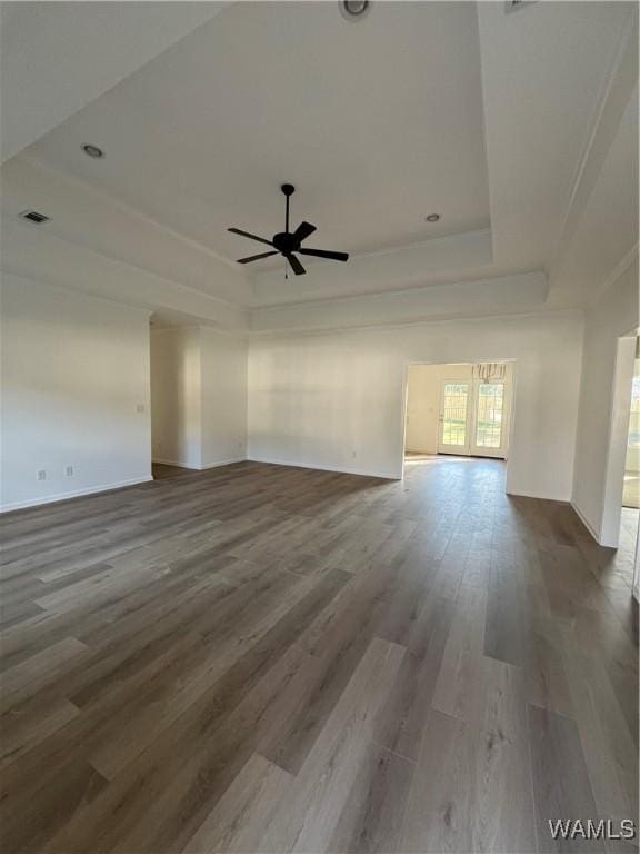 unfurnished living room with wood-type flooring, ceiling fan, and a tray ceiling