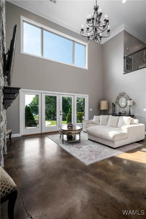 12030 Orlea Ln, Northport, AL 35475 - living area with ornamental molding, a high ceiling, a chandelier, concrete floors, and baseboards