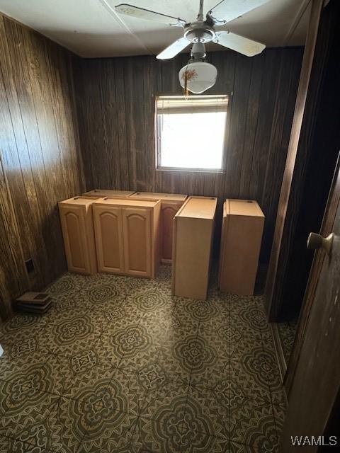 washroom featuring ceiling fan and wooden walls