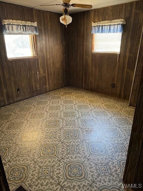 spare room featuring ceiling fan and wooden walls