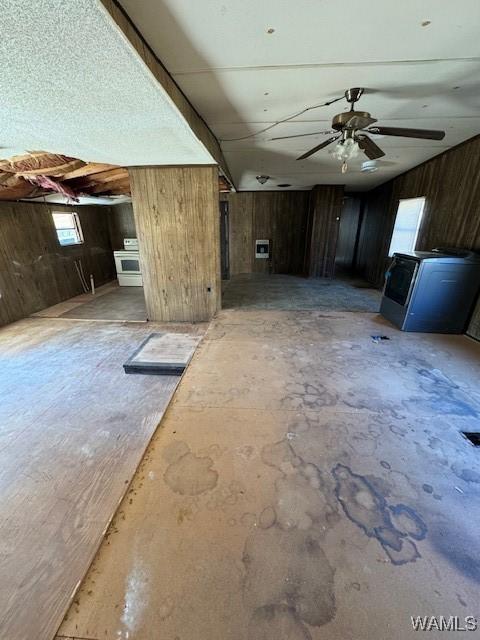 unfurnished living room with ceiling fan and wooden walls