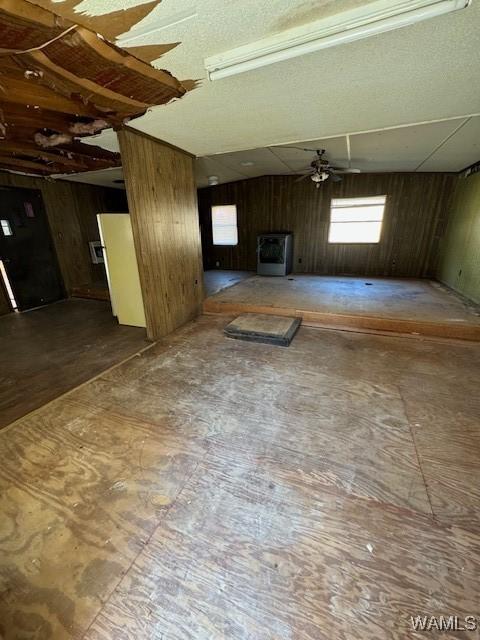 unfurnished living room featuring wood walls and ceiling fan