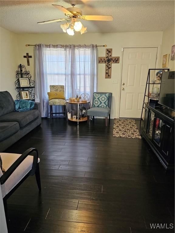 living room with ceiling fan, dark wood-type flooring, and a textured ceiling