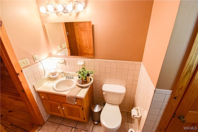 bathroom featuring toilet, vanity, tile patterned floors, and tile walls