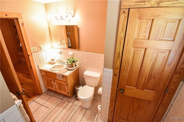 bathroom featuring tile patterned flooring, vanity, toilet, and tile walls