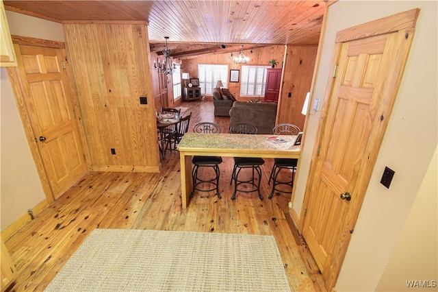 kitchen with decorative light fixtures, a notable chandelier, wooden ceiling, light hardwood / wood-style floors, and wood walls