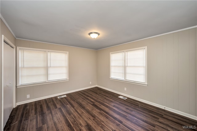 empty room featuring ornamental molding and dark wood-type flooring