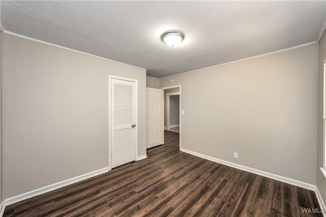 unfurnished bedroom featuring a closet, dark wood-type flooring, and ornamental molding