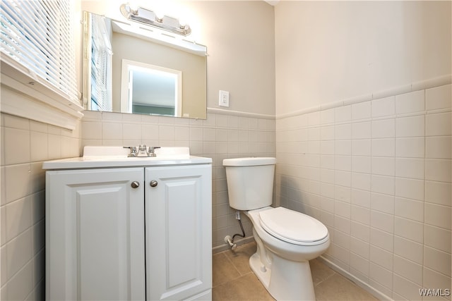 bathroom with tile patterned flooring, vanity, toilet, and tile walls