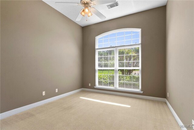 spare room featuring visible vents, light carpet, baseboards, and a ceiling fan