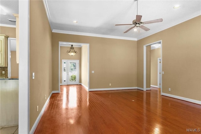 interior space with baseboards, wood-type flooring, ceiling fan, and crown molding