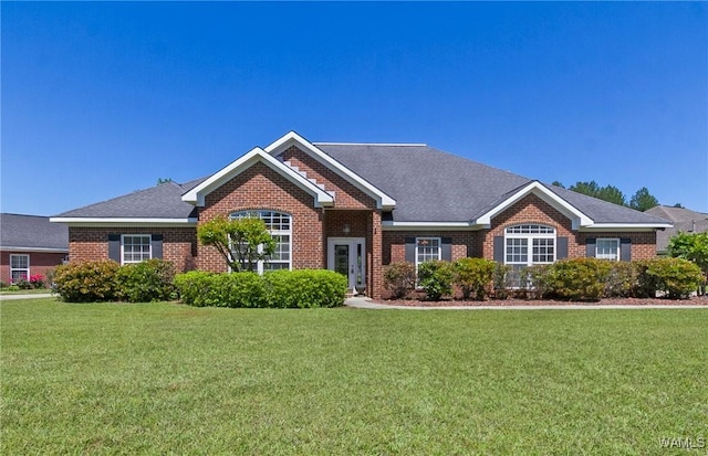 ranch-style home featuring brick siding, a shingled roof, and a front yard