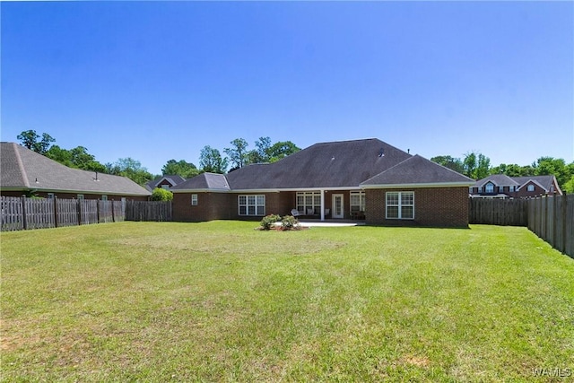 rear view of property featuring a patio area, a lawn, brick siding, and a fenced backyard